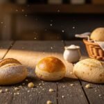 pão francês, pão de sal ou cacetinho — still life com três pãezinhos sobre balcão de madeira em luz matinal